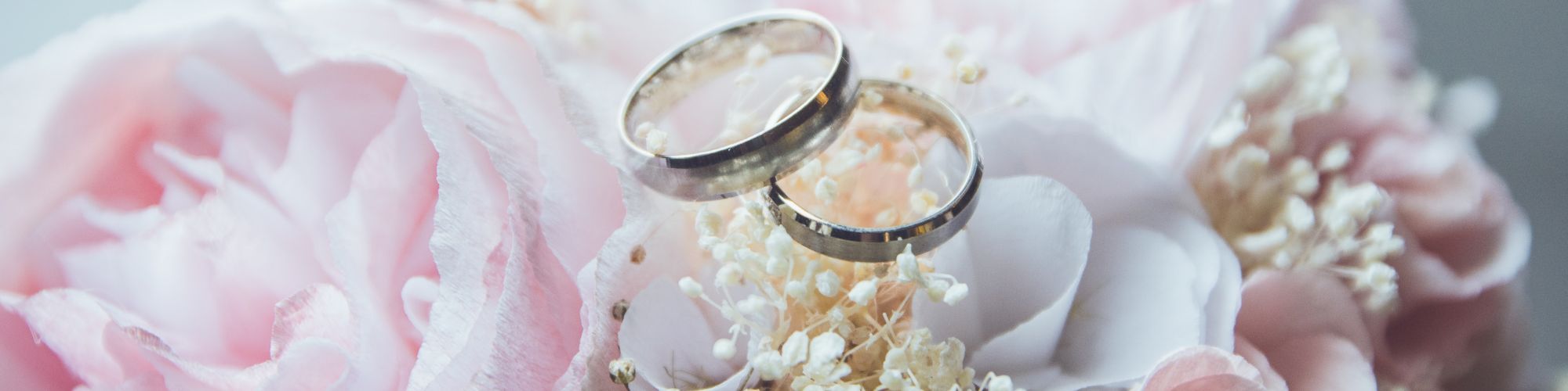 Two wedding rings are placed on a beautiful bouquet of pink and white flowers, creating an elegant and romantic scene.