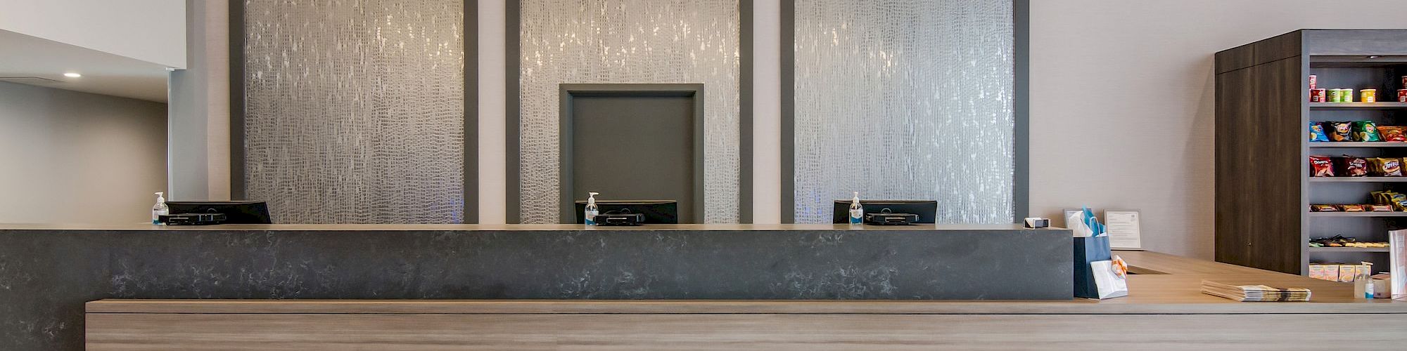 The image shows a modern hotel reception desk with hanging globe lights and a sleek, minimalist design.