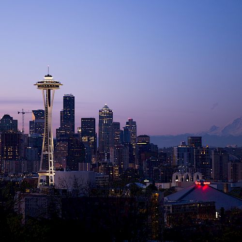 Seattle skyline at twilight with the Space Needle prominently visible; Mount Rainier in the background.